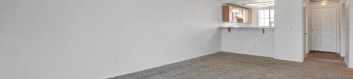 A large empty room with a carpeted floor and white walls.