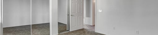 A room with white walls and carpeted floor with a sliding glass door.