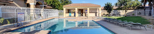 A large outdoor swimming pool with a diving board and a building in the background.