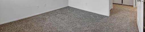 A white room with a carpeted floor and a doorway leading to another room.