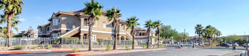 A street view of a residential area with houses and palm trees.