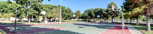 A basketball court with red and green paint and a basketball hoop.