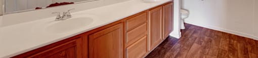 A bathroom with a white sink and wooden cabinets.
