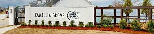 A white building with a sign that says "Camellia Grove" in front of it.