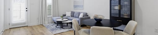 A modern living room with a black coffee table and beige chairs.