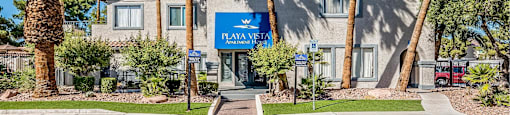 A building with a blue sign that says "PLAYA VIEJO" is surrounded by palm trees.