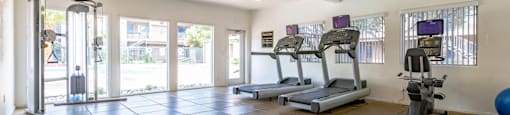 A gym with treadmills, elliptical machines, and a ball.