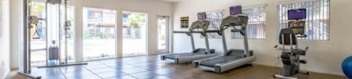 A spacious gym with treadmills, elliptical machines, and a blue exercise ball.