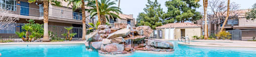 A swimming pool surrounded by palm trees and rocks.