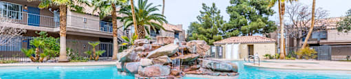 A swimming pool surrounded by palm trees and rocks.