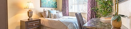 A bedroom with a bed, a chair, a nightstand, and a painting on the wall.