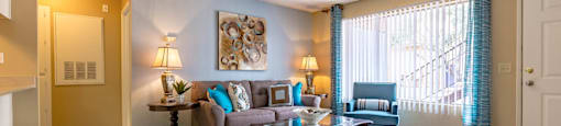 A living room with a couch, a table, and a painting on the wall.