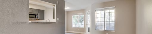 A spacious room with wooden flooring and a kitchen area in the background.