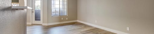 A room with wooden floors and two windows.