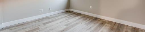 A room with wooden flooring and a window letting in sunlight.