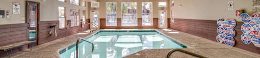 A large indoor swimming pool with a glass divider and a metal ladder.
