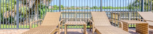 A patio with a table and chairs overlooking a body of water. at Cascades at Clear Lake Apartments, Apartments, Ft. Myers, FL