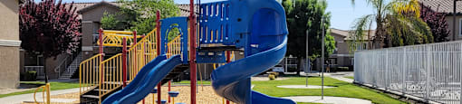 A playground with a blue slide and a yellow railing.