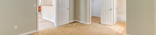 an empty living room with two open doors and a carpeted floor