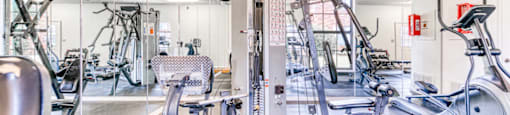 A gym with a variety of equipment including treadmills, weights, and exercise machines.