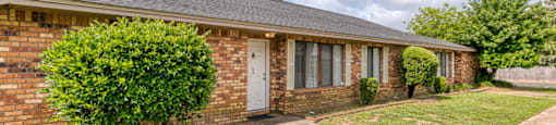 A brick house with a white door and windows.