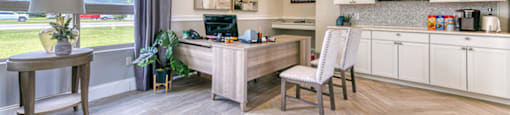 A modern kitchen with a desk and chair in the middle of the room.