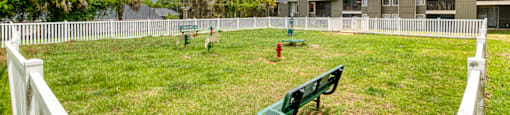 A park with a white fence and a green bench.