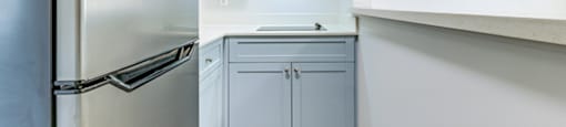 a kitchen with white cabinets and a stainless steel refrigerator