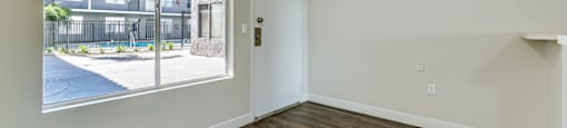 an empty living room with a large window and wood flooring