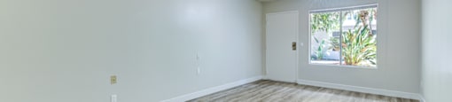 an empty living room with wood floors and a window