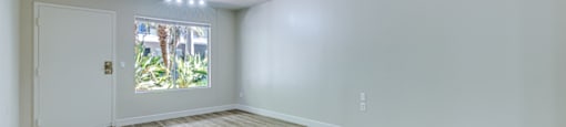 an empty living room with white walls and a window