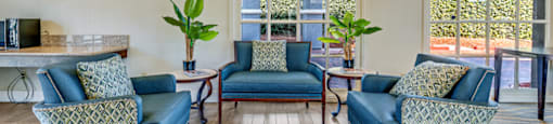 a living room with blue couches and chairs and a window