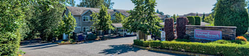 a street view of a house with a driveway and trees