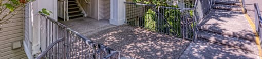 stairs leading up to a house with a sidewalk and trees