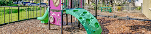 A playground with a pink and green slide. at Westminster Chase Apartments, Florida