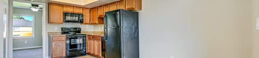 A kitchen with black appliances and wooden cabinets. at Westminster Chase Apartments, Tampa