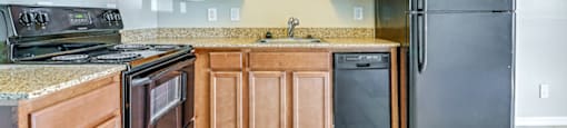 A kitchen with wooden cabinets and black appliances. at Westminster Chase Apartments, Tampa, 33616