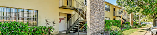 A yellow building with a balcony and a stone pillar. at Westminster Chase Apartments, Florida