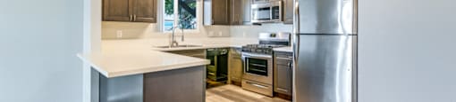 A kitchen with a refrigerator, oven, and microwave.