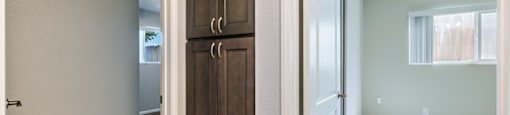 A hallway with a wooden door and a white door.