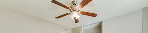 A room with a ceiling fan and a doorway leading to another room.