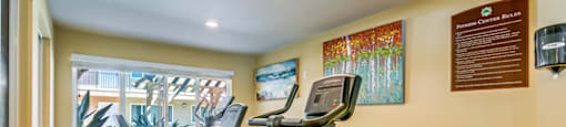 A gym room with exercise equipment and a wooden table.