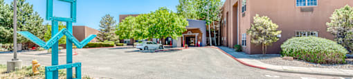 a parking lot in front of a building with a green sign