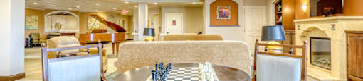 a chess table in a room with chairs and a fireplace