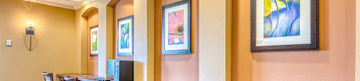 a conference room with a table and chairs and a wall with paintings