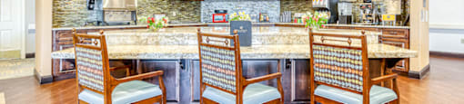 a kitchen with a marble counter top and a bar with chairs
