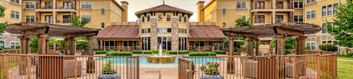 A large apartment complex with a pool and fenced in area.
