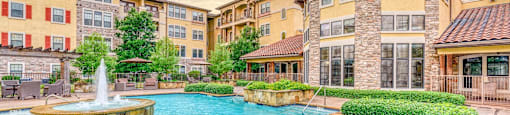 A large outdoor swimming pool with a fountain in the middle of it.