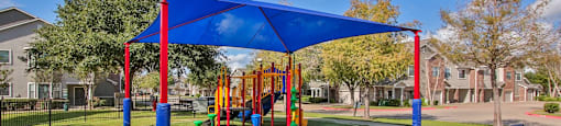 a playground with a blue canopy and benches in a park at Sladestone Shadow Creek, Pearland, TX, 77584