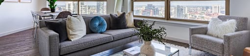 a living room with a couch and a glass coffee table and large windows at Presidential Towers in Chicago, IL